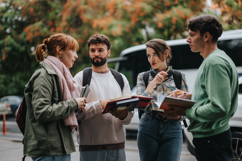 Group of students discussing with books outdoors Soziale Gruppe